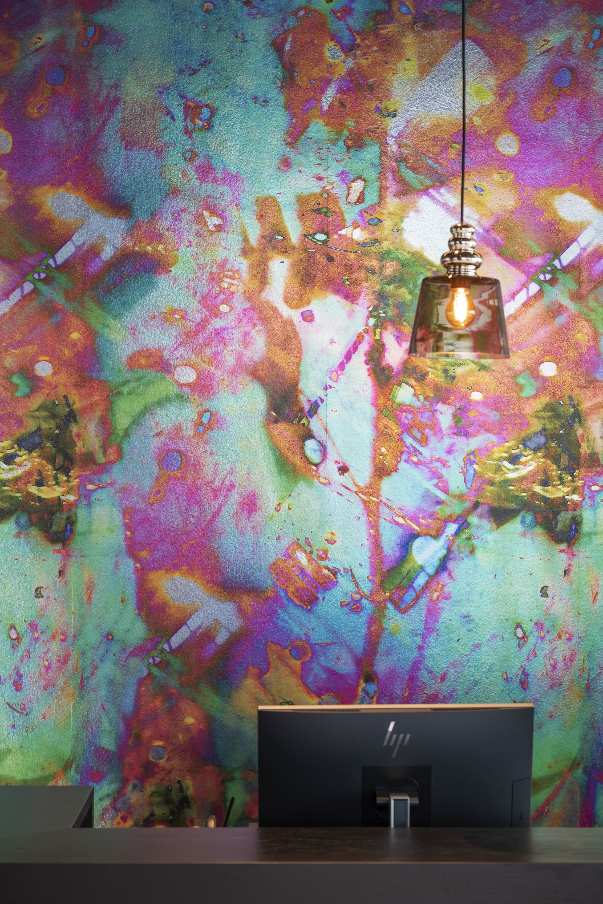 Un interior moderno con un vibrante mural abstracto y un escritorio con una computadora.