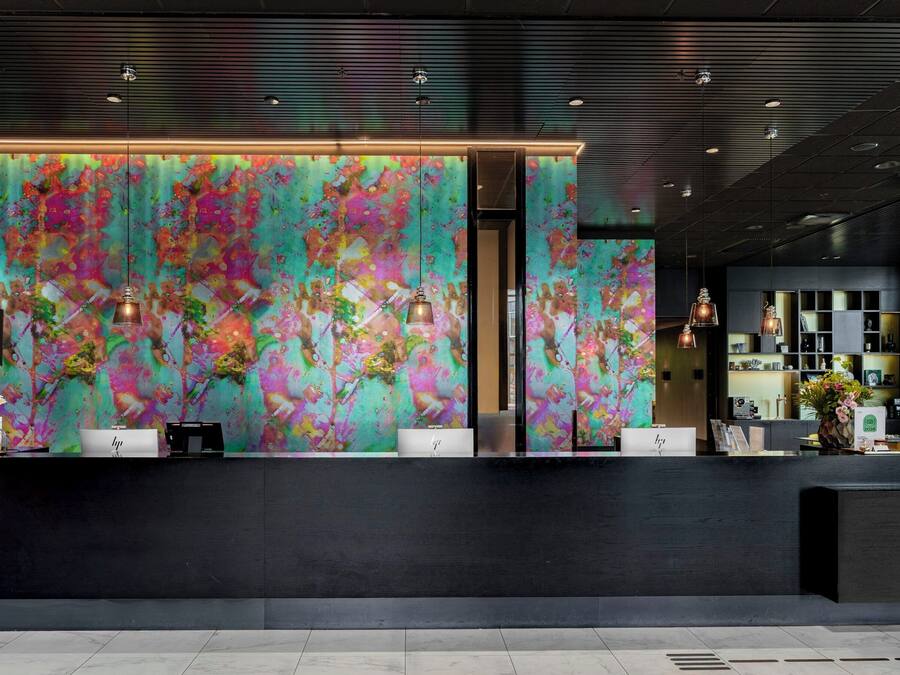 Zona de recepción con un mural abstracto de colores, un mostrador negro y una decoración de diseño moderno.