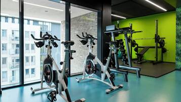 A gym with stationary bikes, a squat rack, and a green wall.