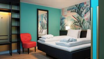 A bedroom with a bed, a red chair, a bookshelf, and a large mirror.