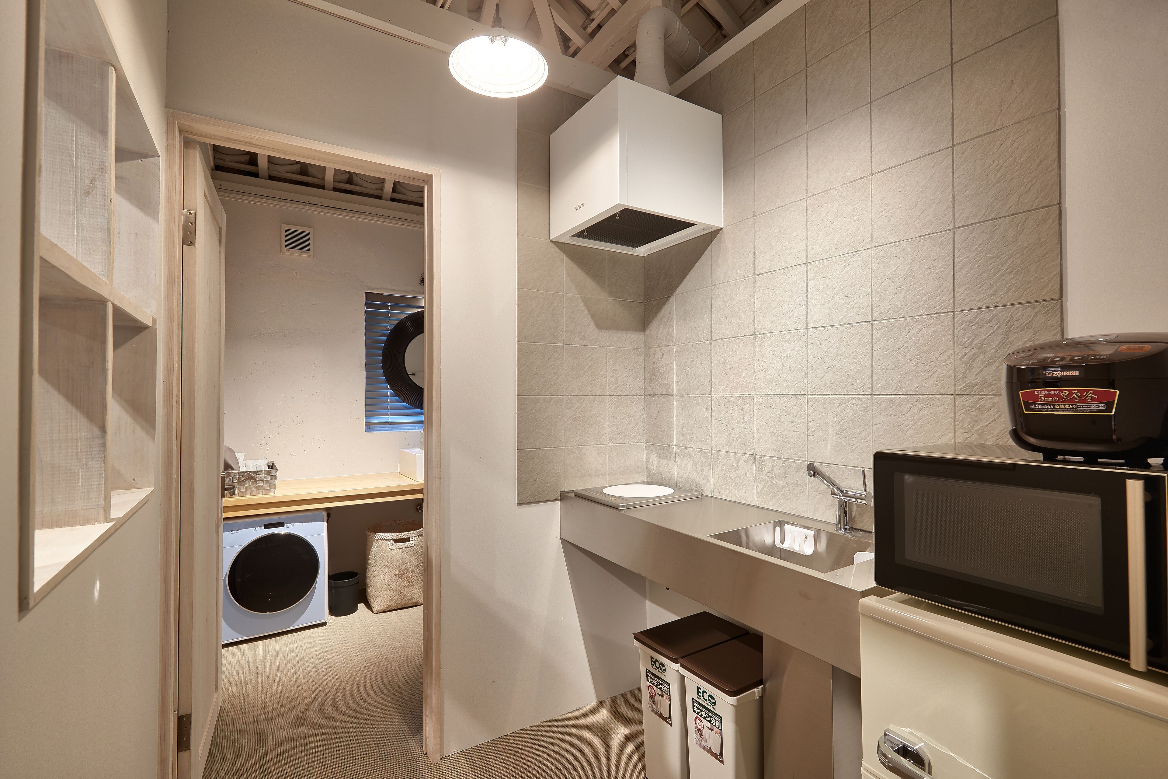 Un baño moderno y funcional con lavadora integrada, microondas y lavamanos.