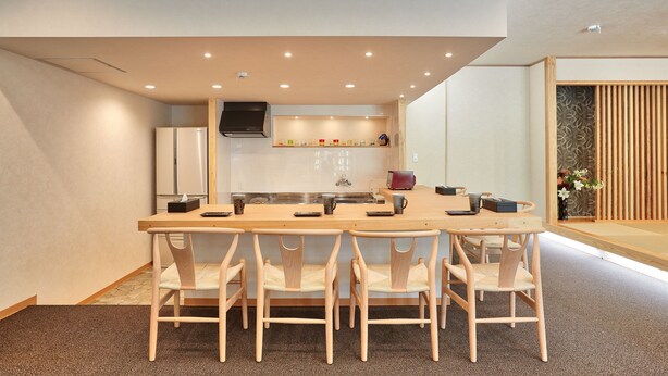 Una cocina moderna con una isla central, sillas de madera y una mesa de comedor.