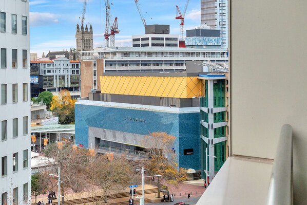 A modern building with a prominent yellow and blue facade, a cinema sign, and a clock tower in the background. - Chic & Stylish Apartment with Parking (Auckland)
