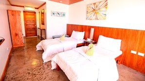 A hotel room with two beds, wooden headboard, a small table, and a painting on the wall. - Allura Resort Dive and Spa (Zamboanguita)