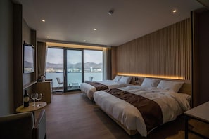 A modern hotel room with two beds, a dining area, and a view of the sea. - Masan Tourist Hotel (Changwon)