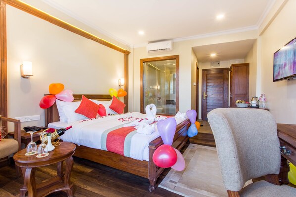 Een hotelkamer met een houten bed, een klein tafeltje met een fles en glazen, en een stoel.