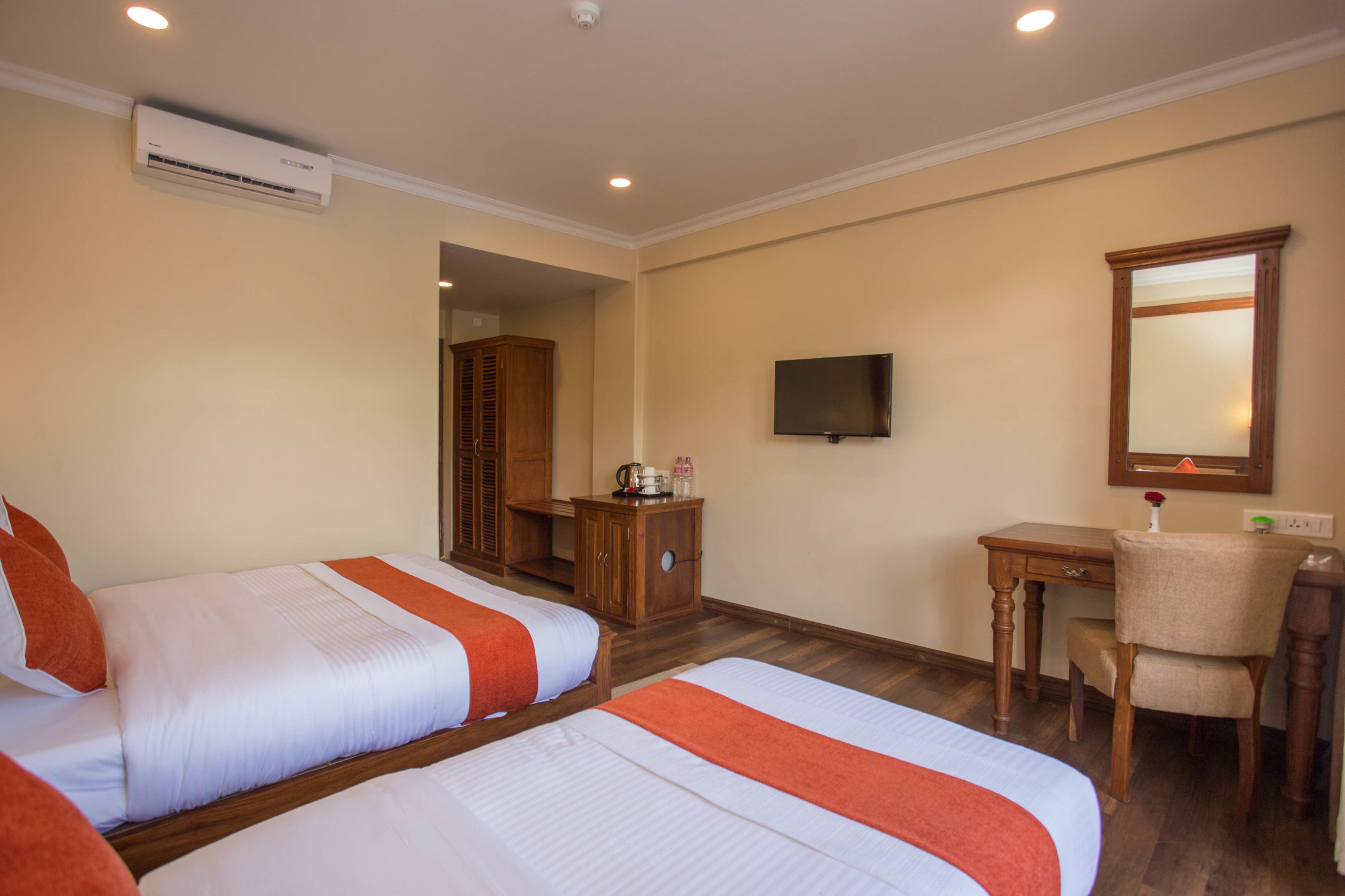 Une chambre d’hôtel avec deux lits, un bureau, une chaise, une télévision et un miroir.