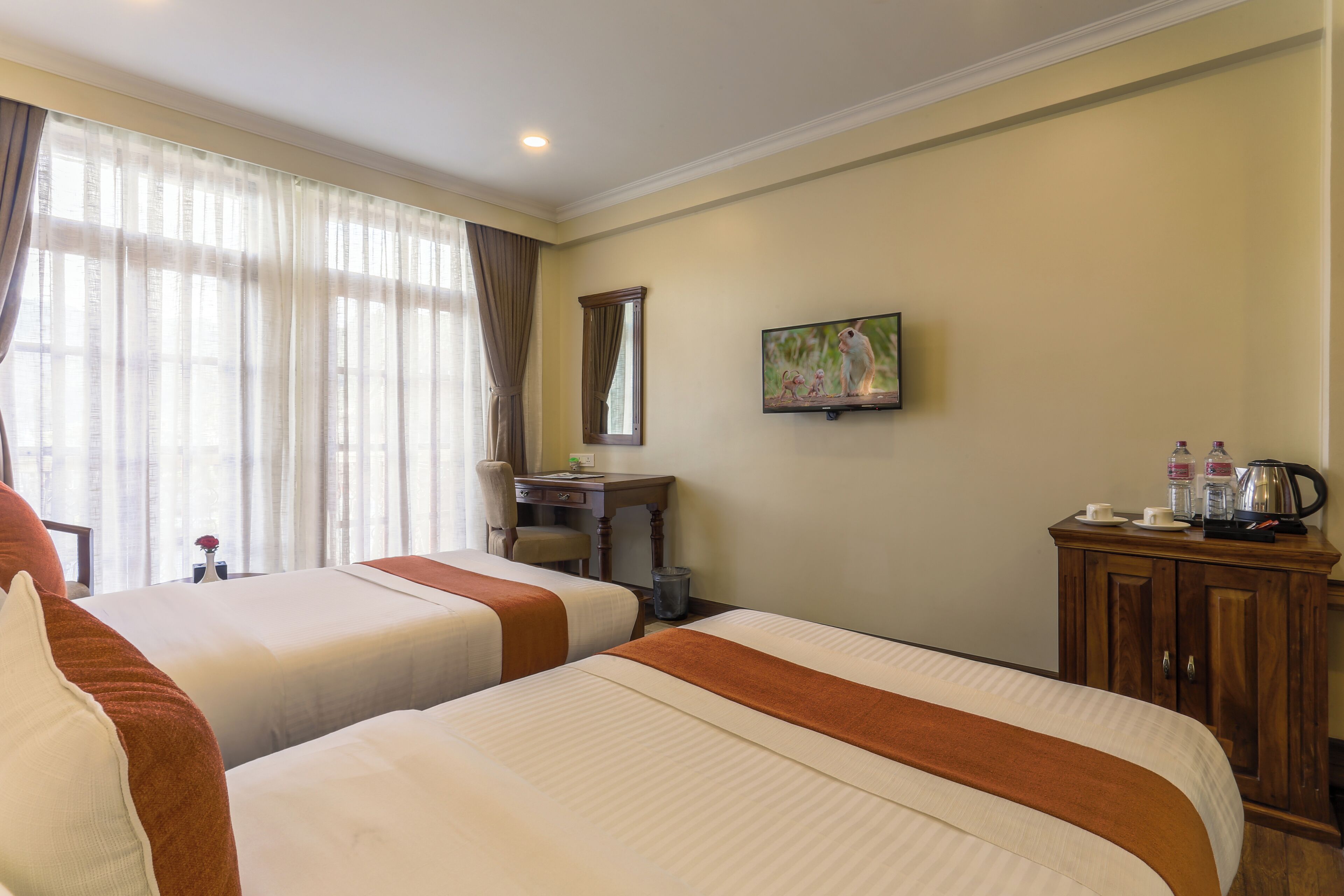 Una habitación de hotel con dos camas, un escritorio, una televisión y un armario.