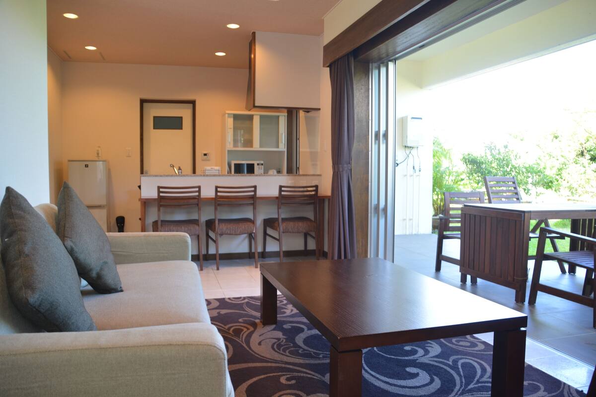 Quarto de hotel moderno com sofá, mesa de jantar e cozinha.