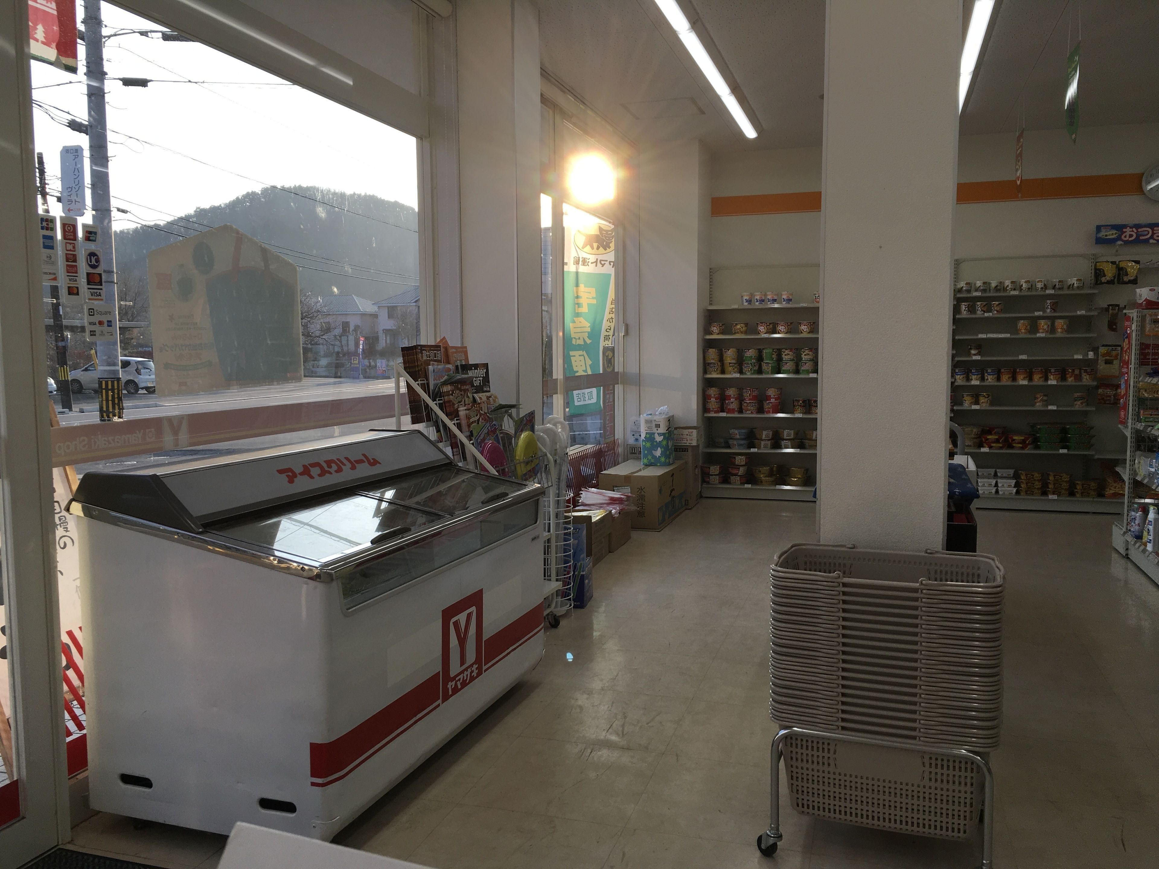 Interior de una farmacia con un refrigerador, estantes llenos de productos y una zona de caja visible.