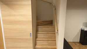A wooden staircase with a handrail, leading to a landing with a bench and a small table. - Rental Villa Ooishiso (Fujikawaguchiko)