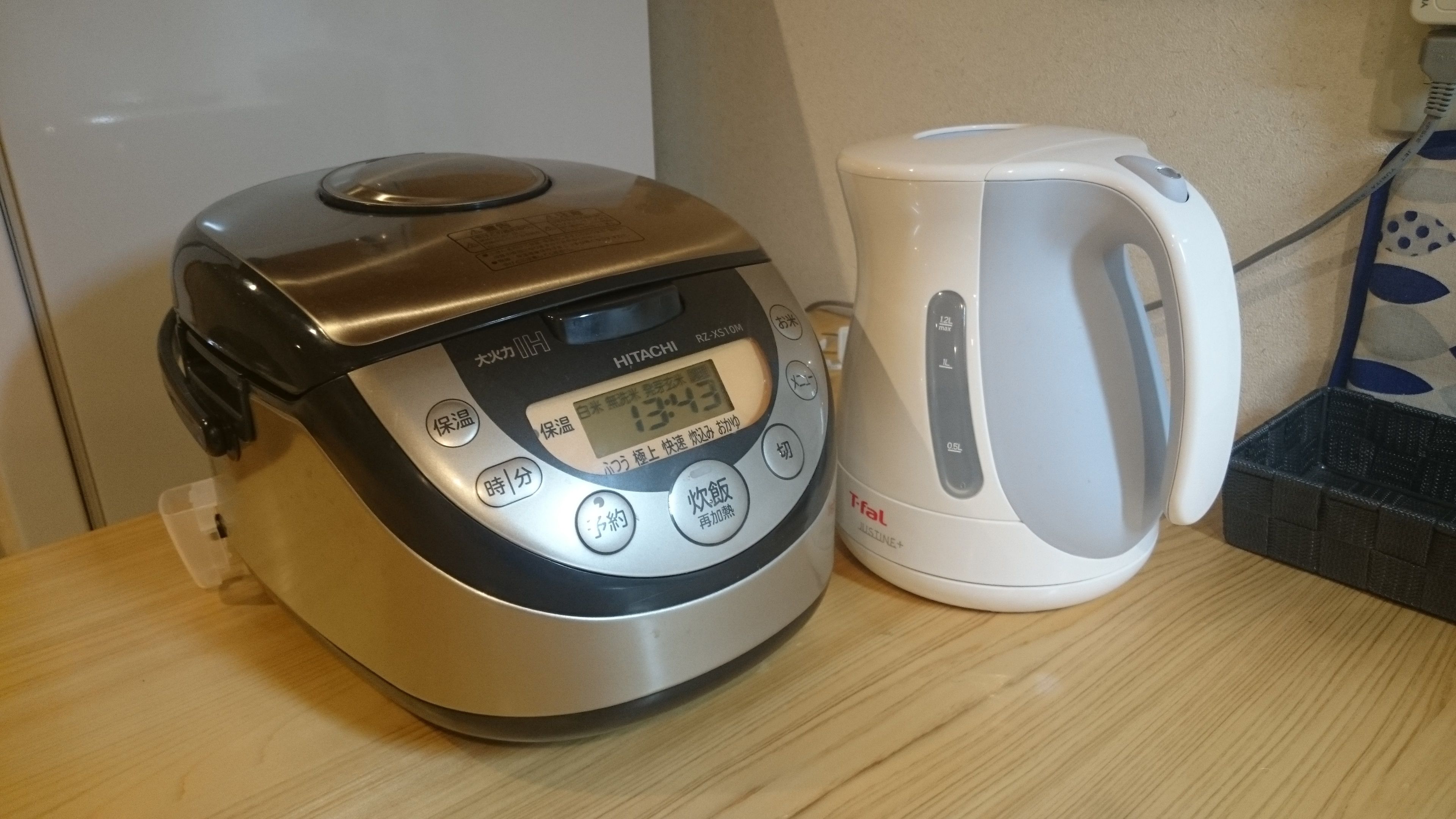 Un appareil de cuisine doté d’un écran numérique et de boutons, placé à côté d’une bouilloire électrique blanche sur une surface en bois.