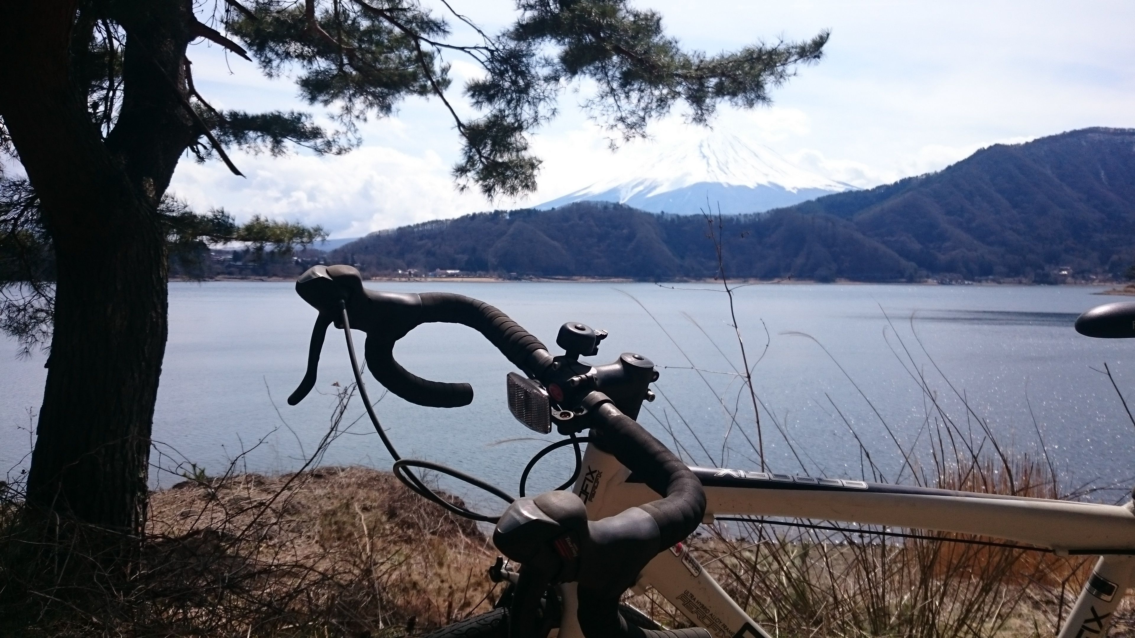 A bicycle parked near a lake with a mountain in the background.