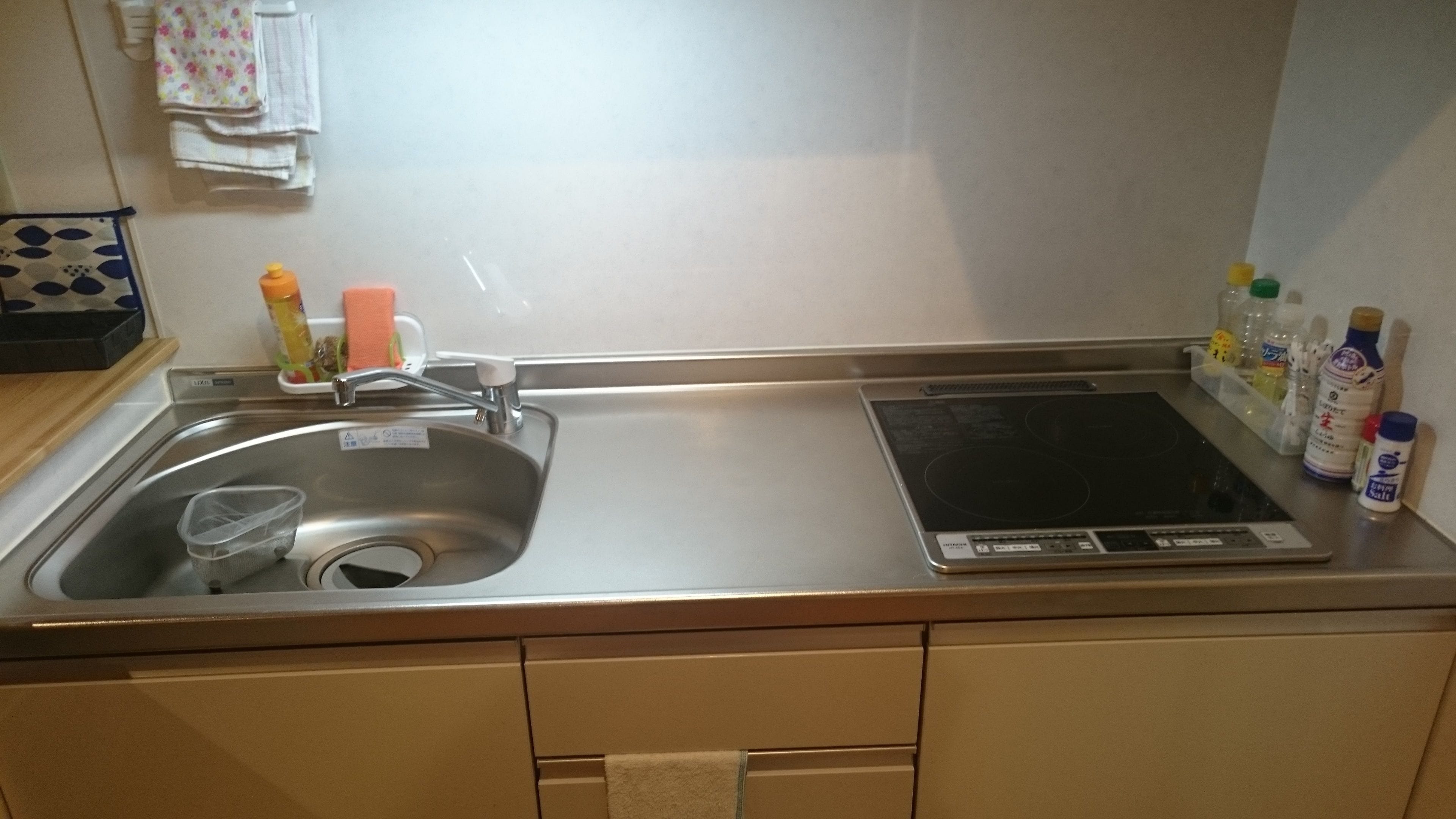 Una cocina con un lavamanos de acero inoxidable, una balanza empotrada y diversos utensilios de cocina sobre la encimera.