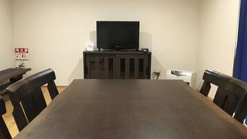 A conference room with a large table, chairs, a television on a cabinet, and a fire extinguisher on the wall.