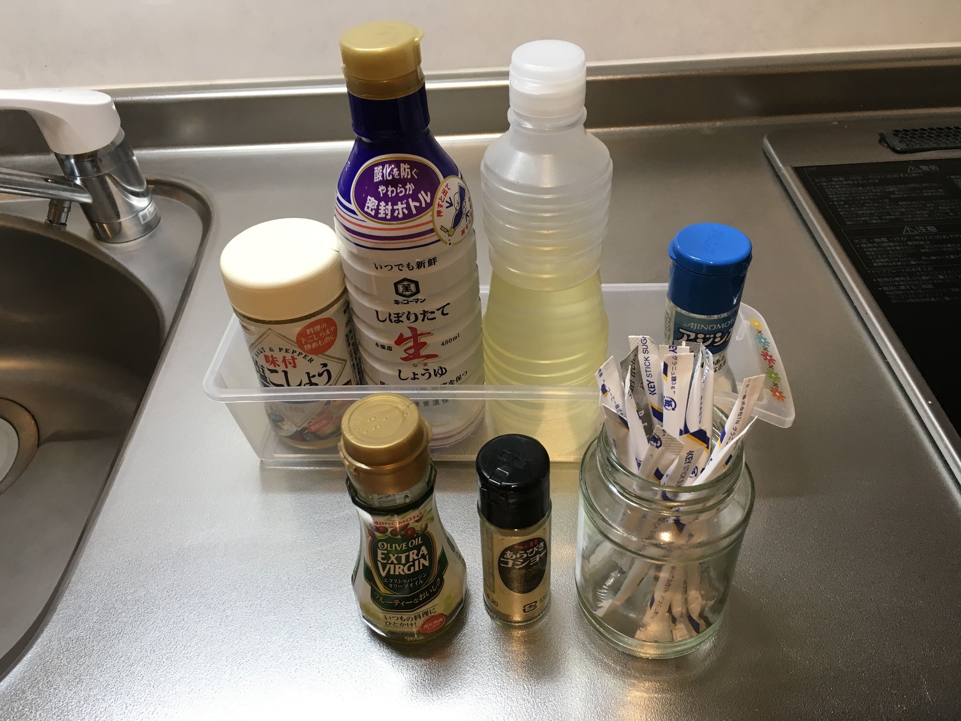 A kitchen counter with various condiments and a jar of sugar packets.