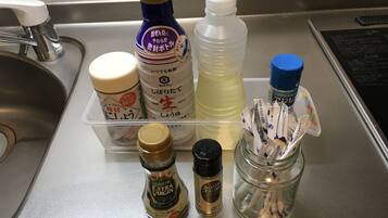 A kitchen counter with various condiments and a jar of sugar packets.