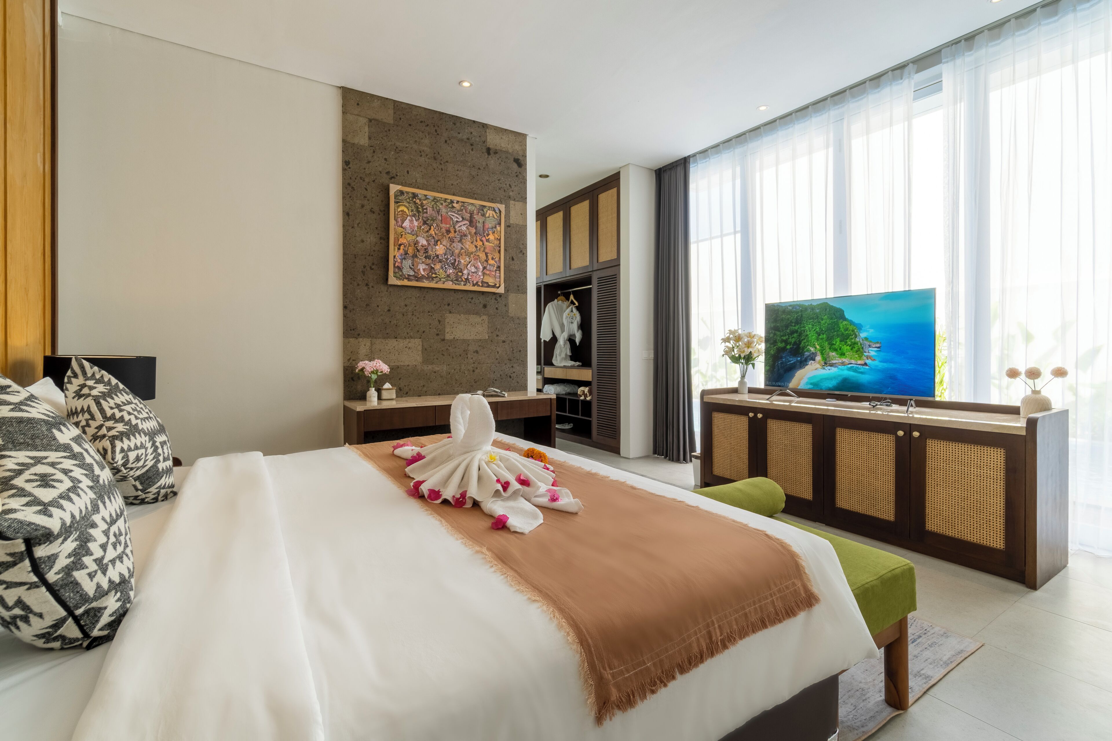 Une chambre d’hôtel moderne dotée d’un grand lit, d’une télévision, d’une armoire et offrant une vue sur la mer.
