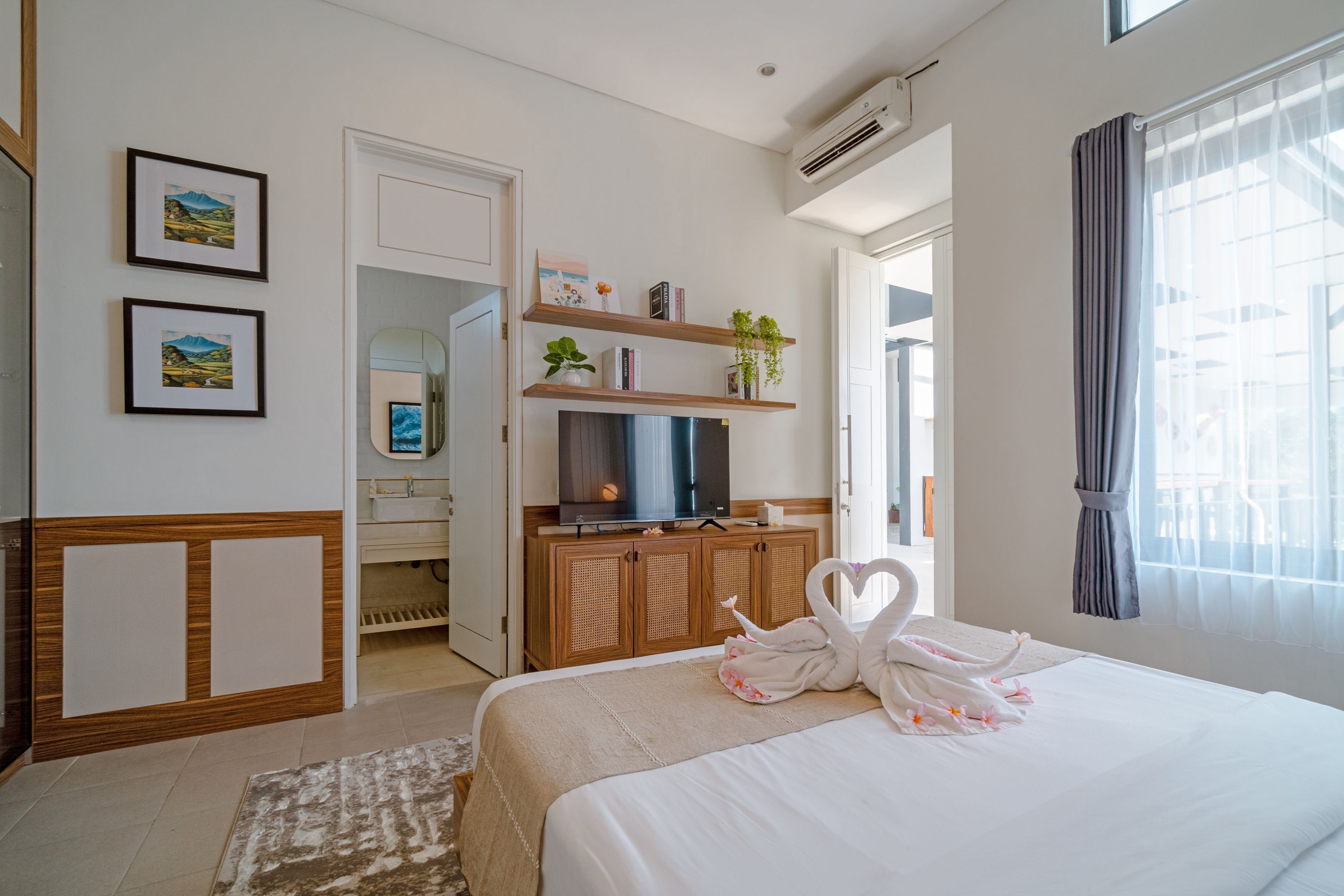 A hotel room with a bed, a television, a wardrobe, a mirror, and a window with curtains.