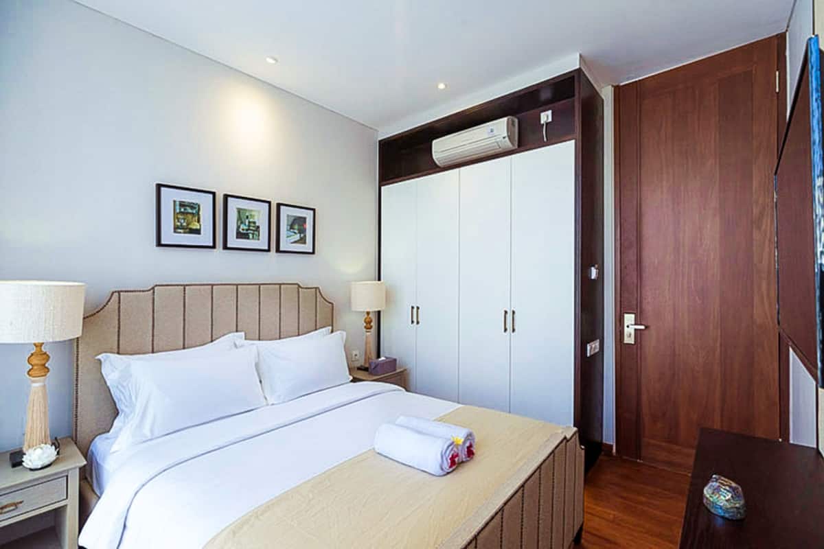 Une chambre d’hôtel avec un lit, des tables de chevet, une armoire et des tableaux encadrés au mur.