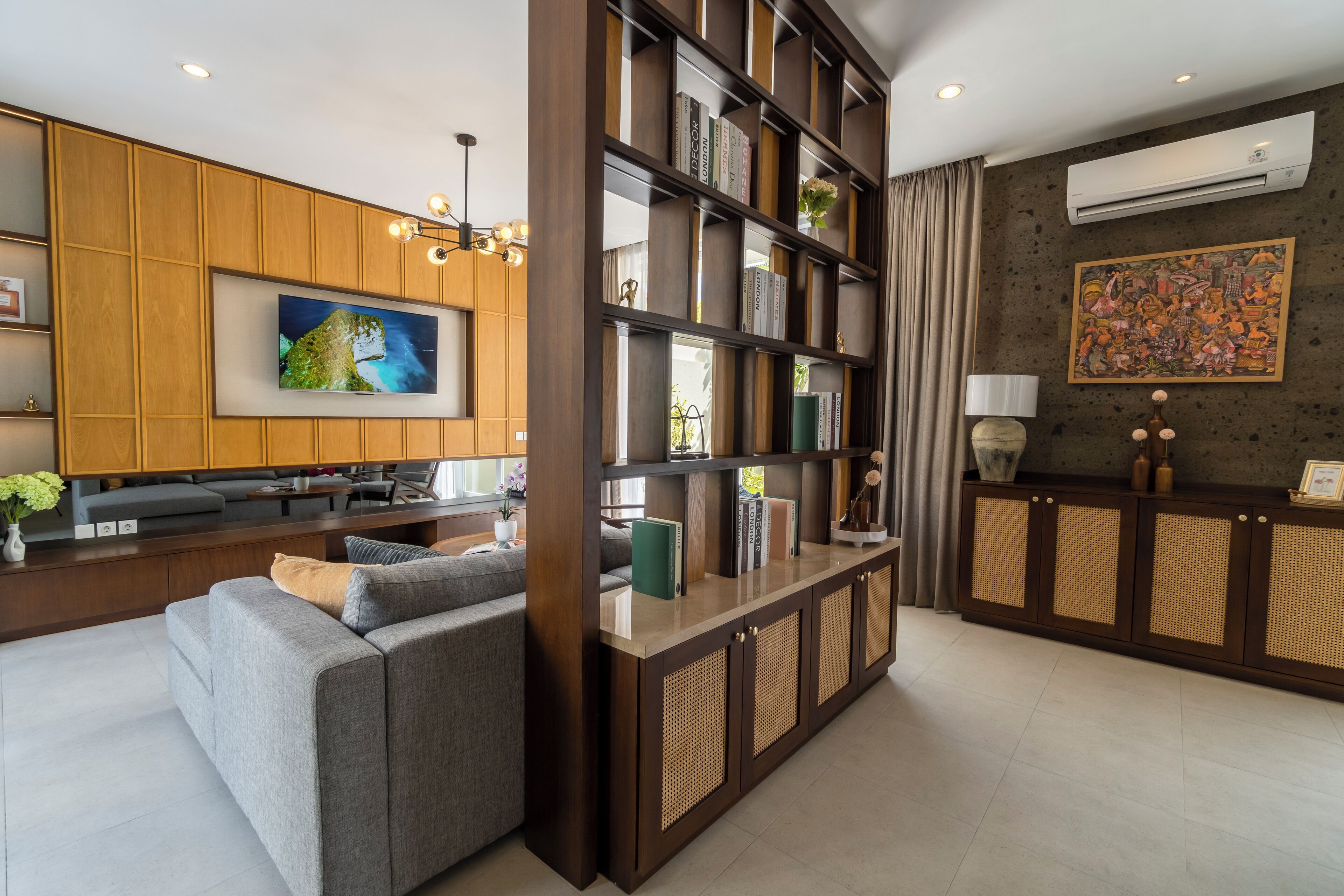 A modern living area with a sofa, a television, a bookshelf, and a decorative wall.