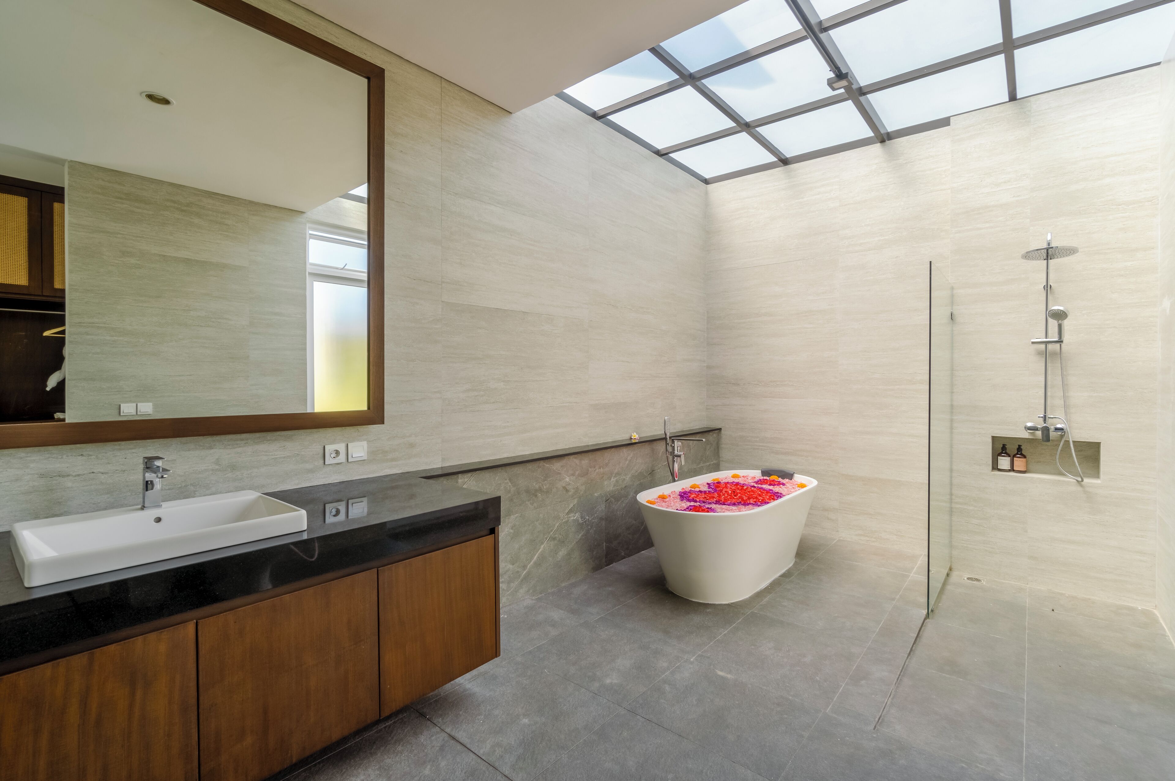 Une salle de bain moderne dotée d’un puits de lumière, d’une baignoire sur pieds et d’un grand miroir.