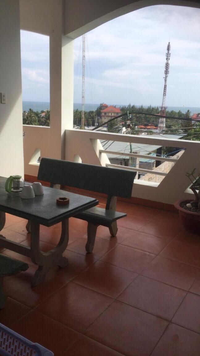 A balcony with a table and chairs, a potted plant, and a view of the cityscape.