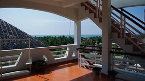 Un balcón amplio con vista despejada al océano y palmeras.
