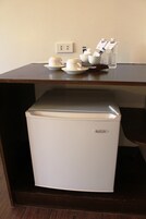 Un refrigerador pequeño con exterior blanco y parte superior plateada, sobre una mesa de madera.