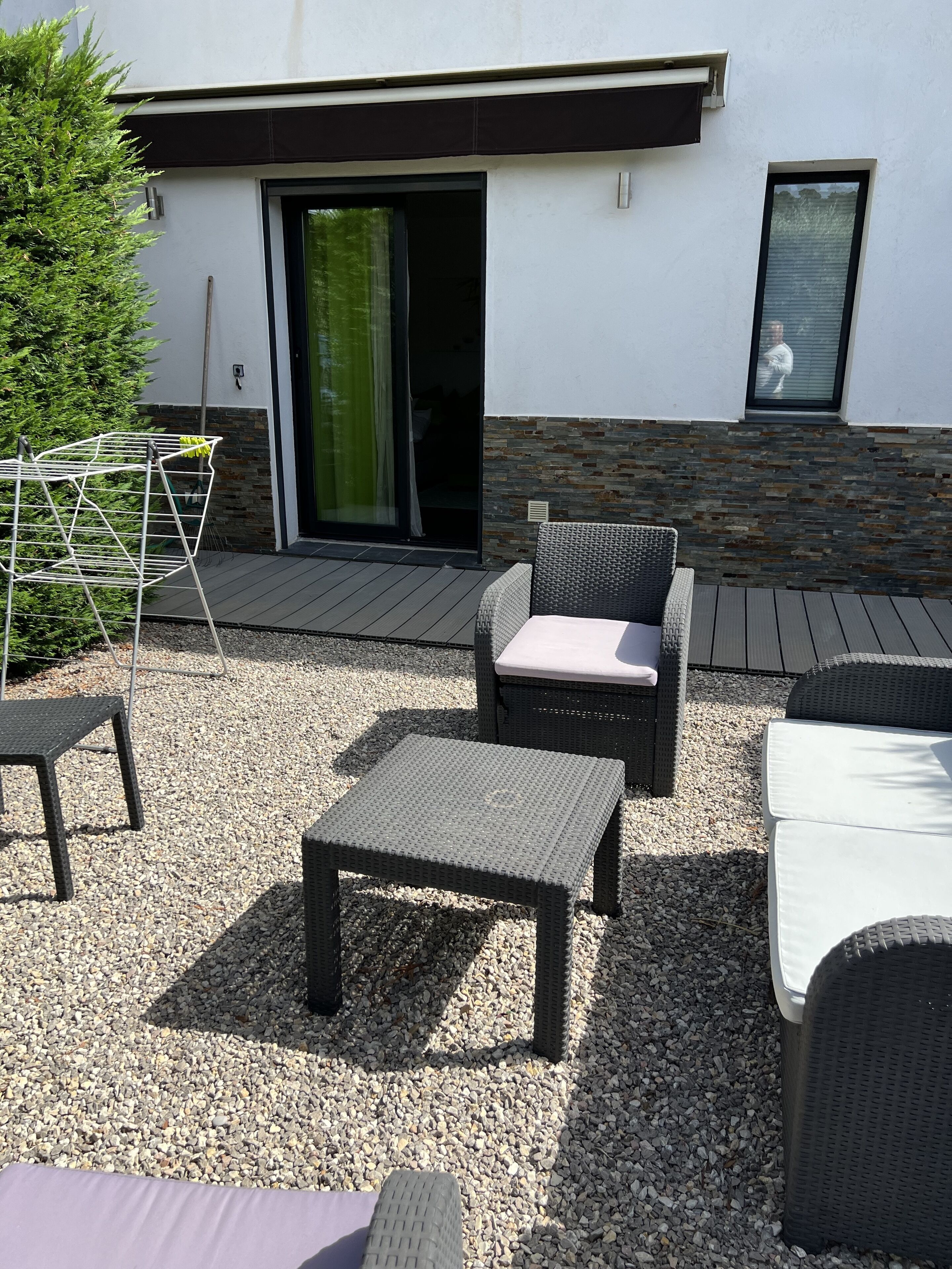 An outdoor patio with wicker furniture, a drying rack, and a small table.