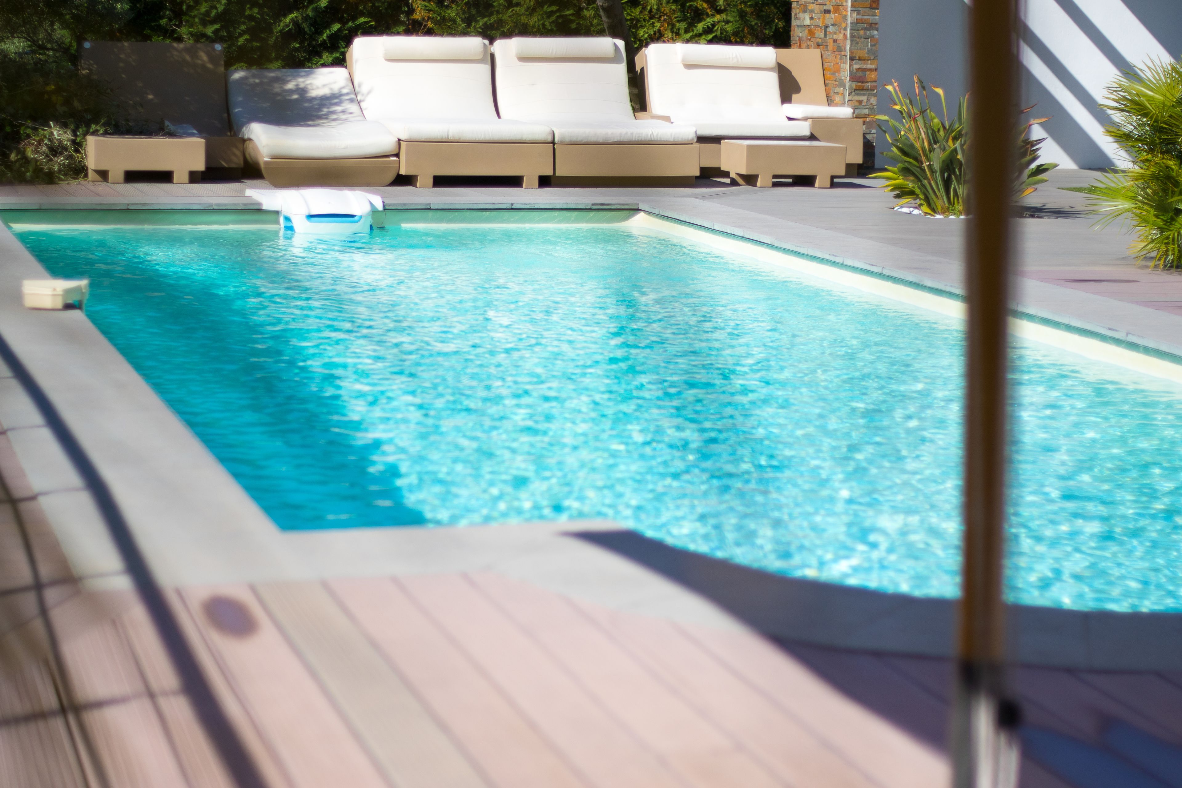 A swimming pool with lounge chairs and a wooden deck.