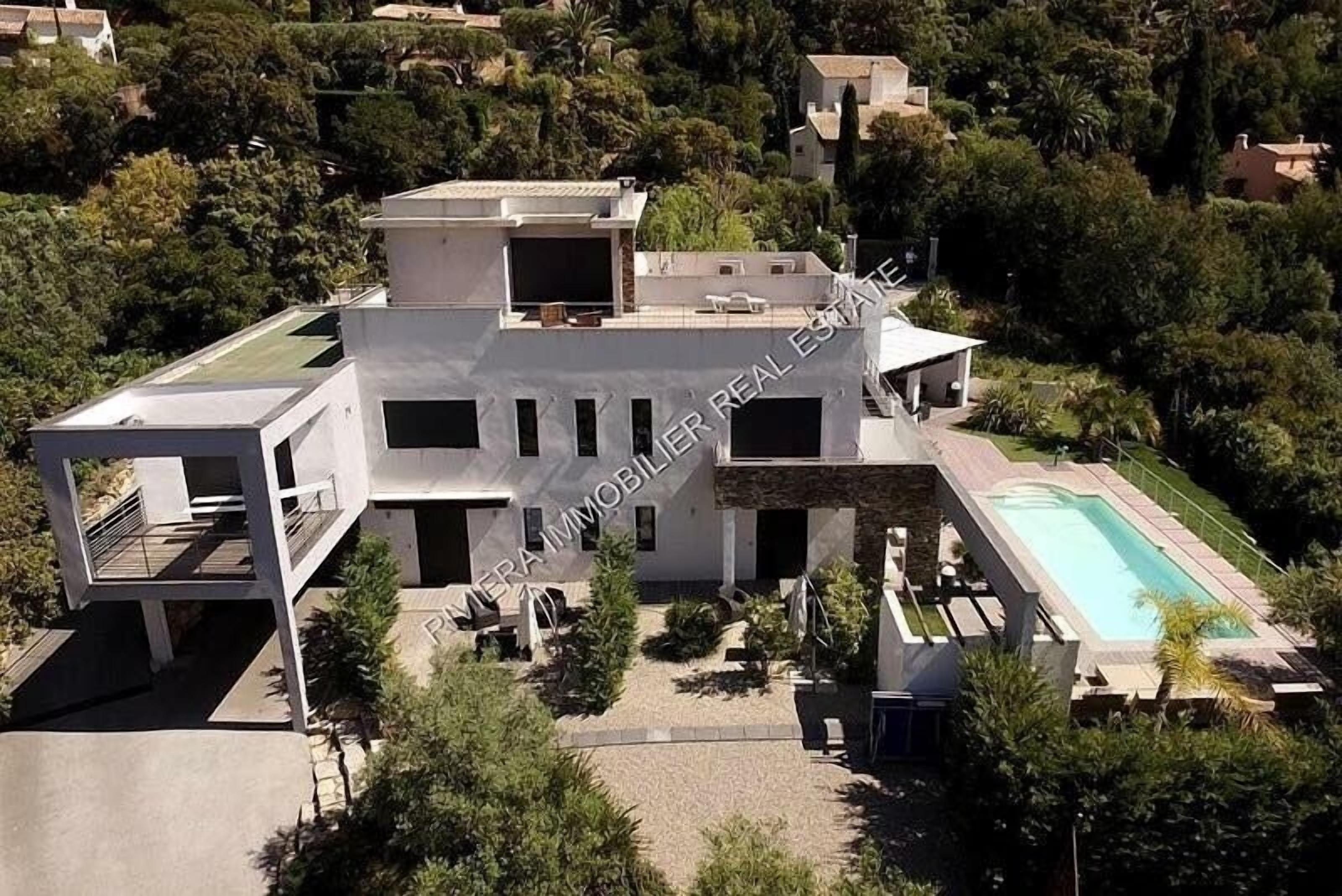 Una casa moderna de dos pisos con piscina, rodeada de vegetación.