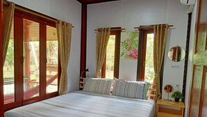 Un dormitorio con una cama grande, cabecera de madera y cortinas. Hay una mesita de noche con una lámpara y una planta pequeña.