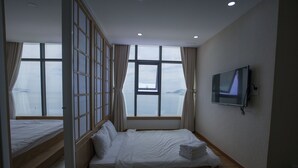 Une chambre d’hôtel avec deux lits, une télévision et de grandes fenêtres donnant sur la mer.