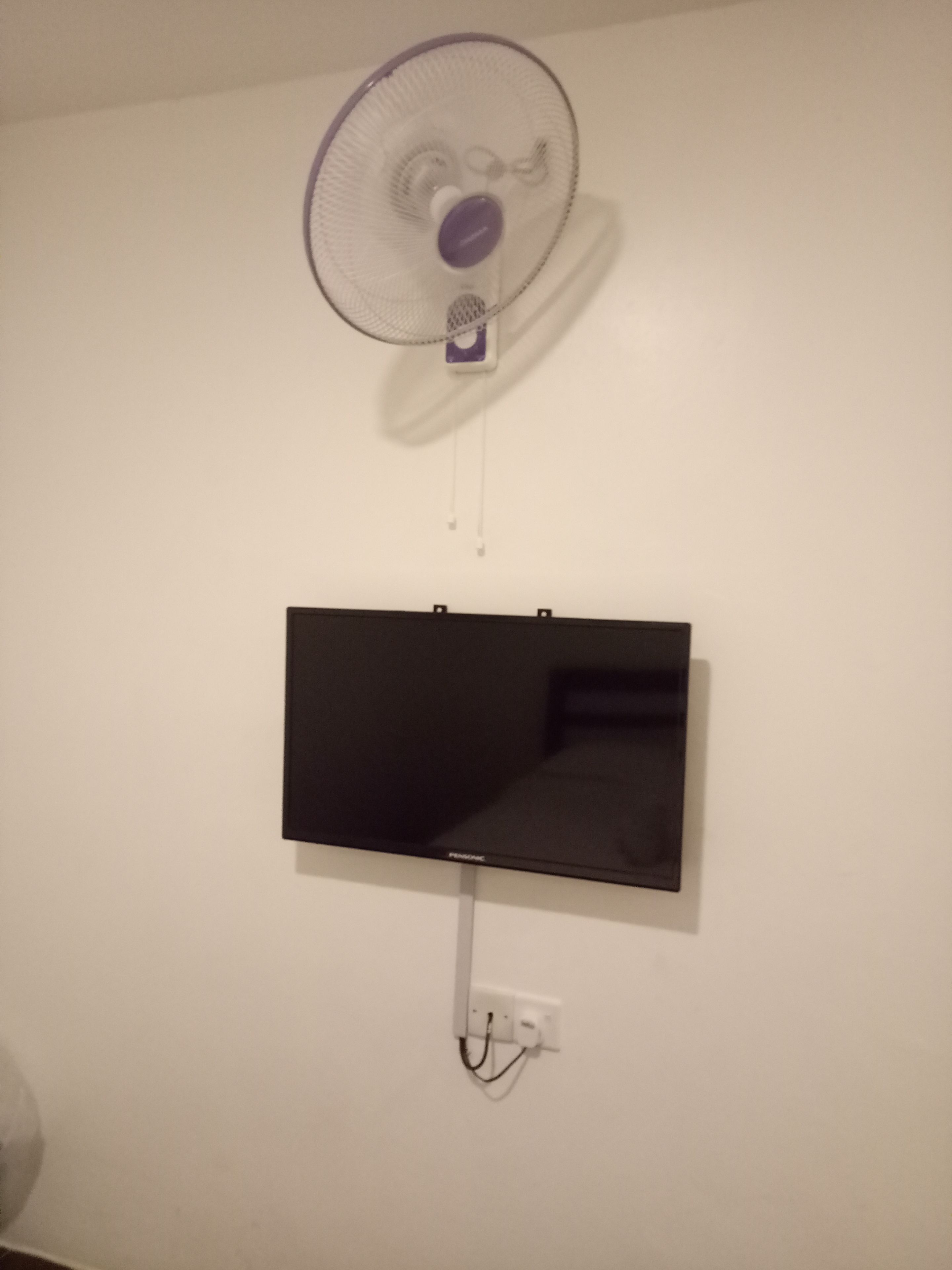 A wall-mounted TV and a ceiling fan.