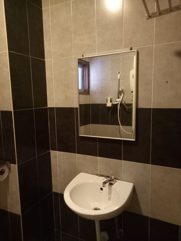 A bathroom with a white sink, a mirror, and a shower head. - Hotel Sri Bernam (Sabak)