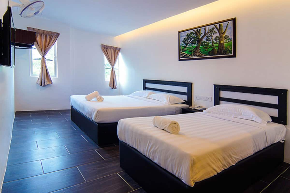 Ein Hotelzimmer mit zwei Betten, einem Flachbildfernseher und einem Bild an der Wand.