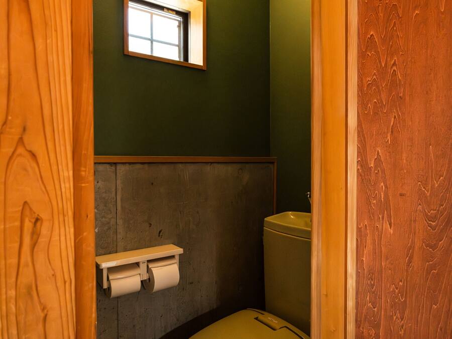 A small bathroom with a toilet, a hand dryer, and a window.