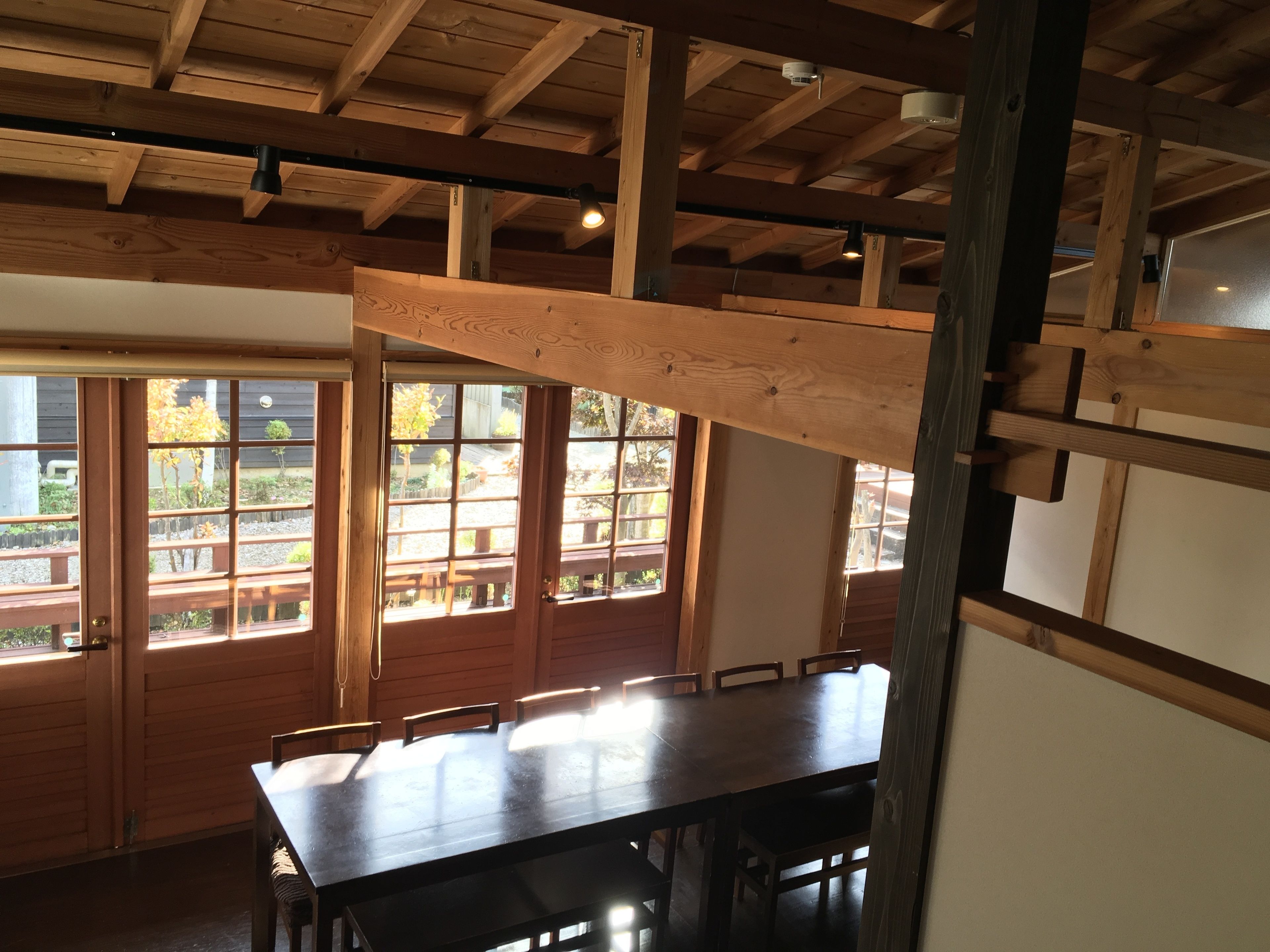 A wooden dining area with a high ceiling and large windows.