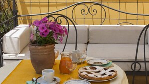 A table set with a plate of food, a pitcher of drink, a cup, and a flower pot.