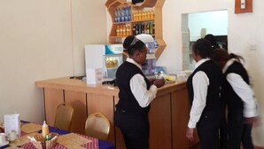 A bar area with a counter and shelves stocked with beverages. - The Salmuc Hotel (Njoro)