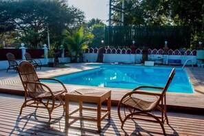 A rectangular swimming pool with a wooden deck, surrounded by a low fence and palm trees. - Lawkanat Hotel (Nyaung-U)