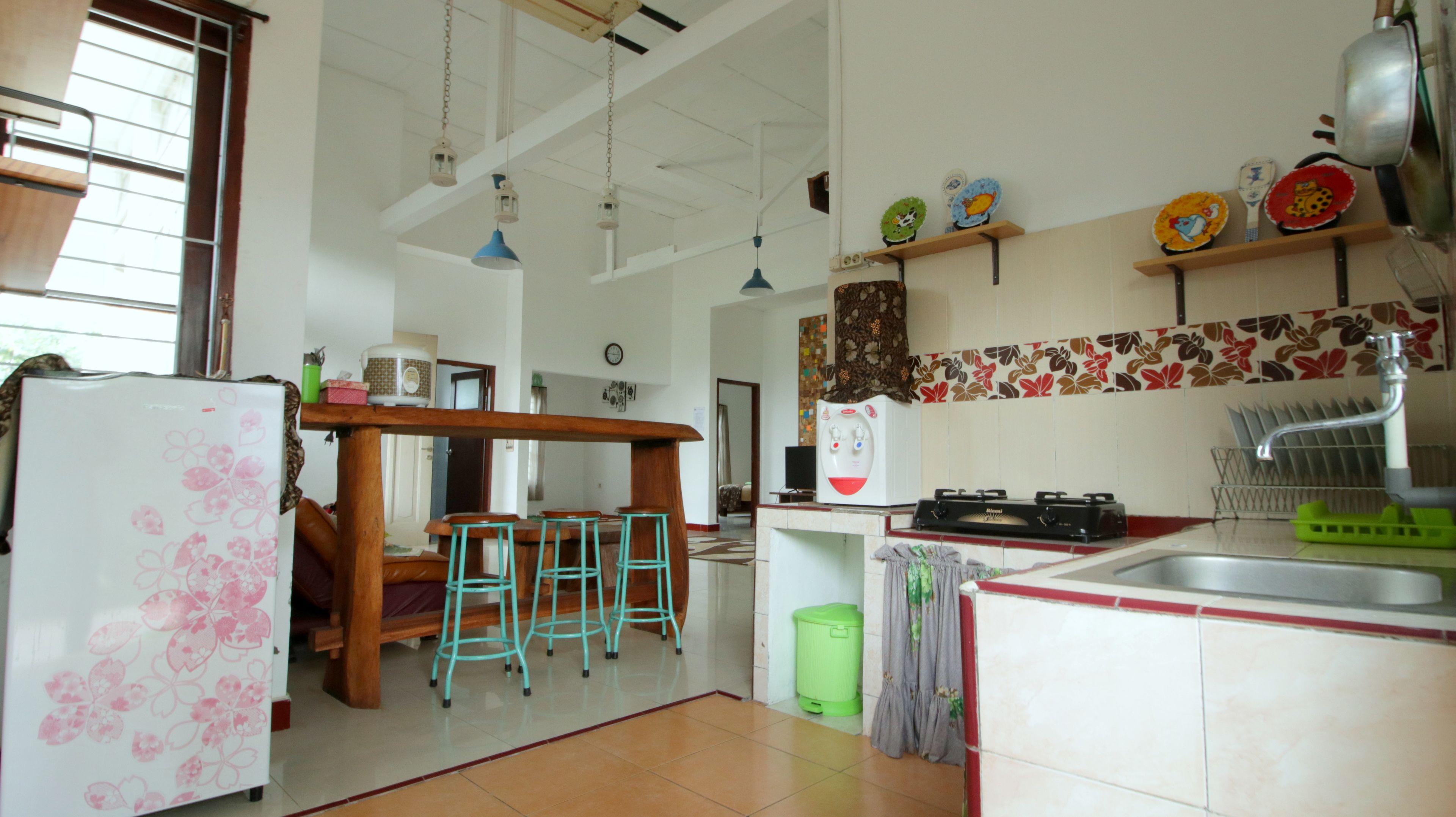 A kitchen with a refrigerator, stove, sink, and bar stools.