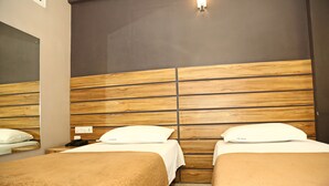A hotel room with two beds, wooden headboard, white bedding, and a nightstand with a phone. - Vajra Heritage (Bengaluru)