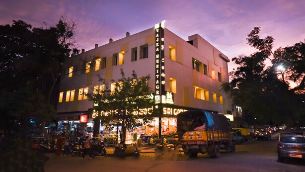 A multi-story building with illuminated signage, a vertical sign on the corner, and a ground-level entrance with a canopy. - Vajra Heritage (Bengaluru)
