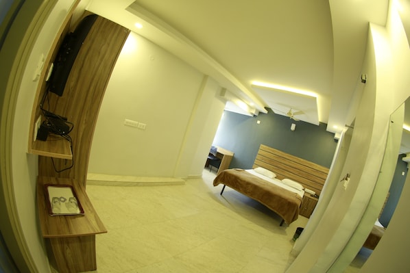 A bedroom with a bed, a desk, and a chair. - Vajra Heritage (Bengaluru)