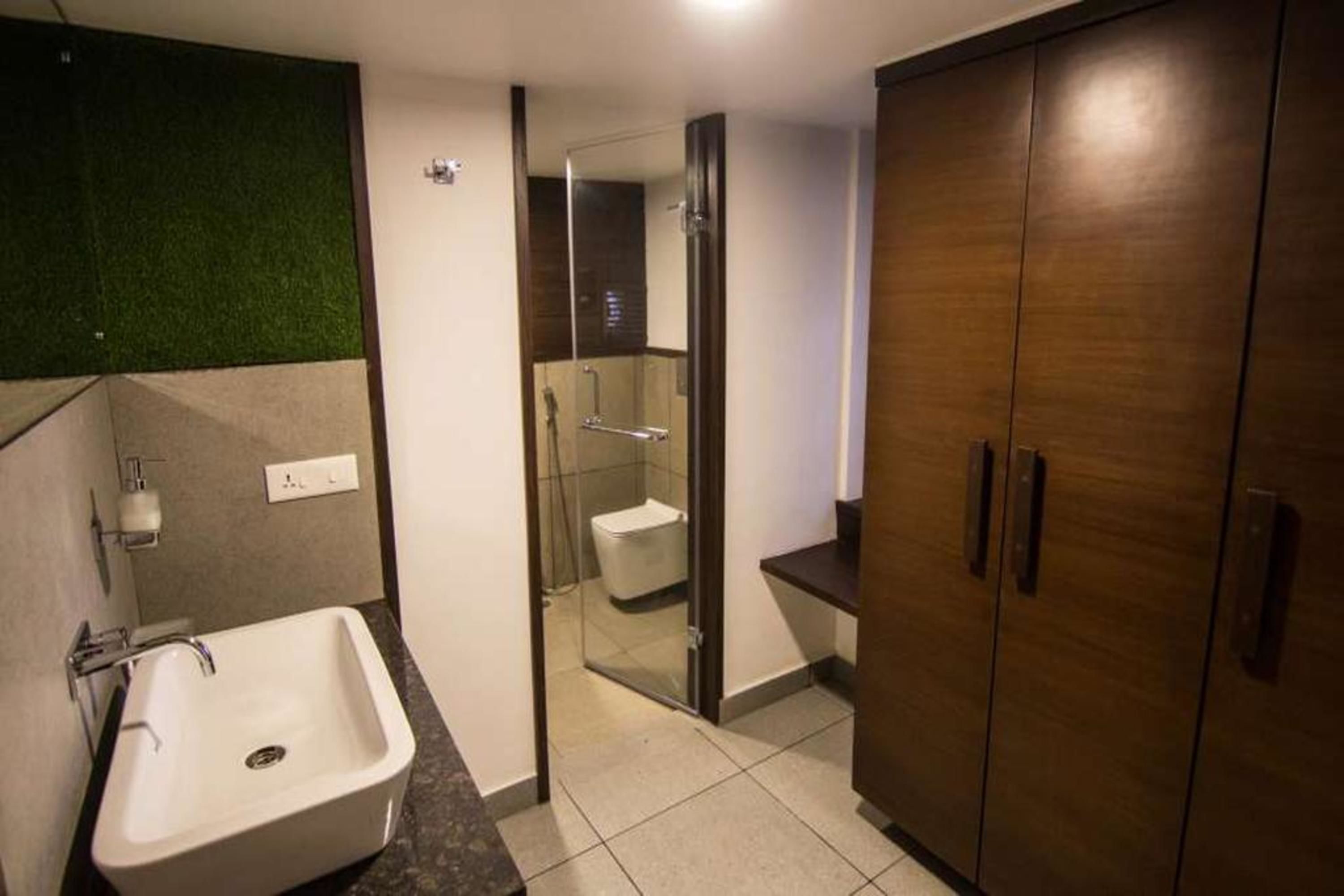 A bathroom with a white sink, a glass shower enclosure, and wooden cabinets.