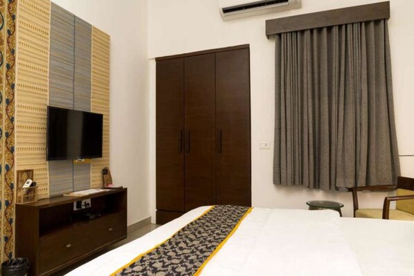Une chambre à coucher avec un lit, une armoire, un téléviseur et un rideau.