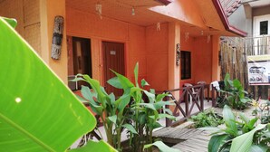 A wooden building with a covered porch, a wooden deck, and various plants. - Forest Inn (El Nido)