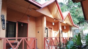 A wooden building with a red roof and a covered porch area. - Forest Inn (El Nido)
